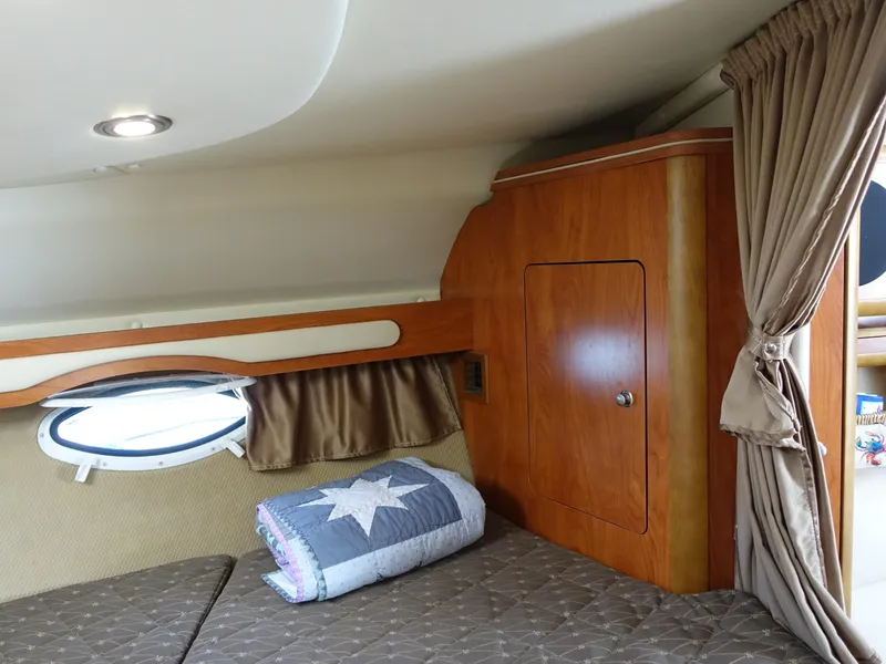 Slide: The Image of 2008 Rinker 330 Express Cruiser cabin interior with bed, wooden cabinet, and porthole. - 7