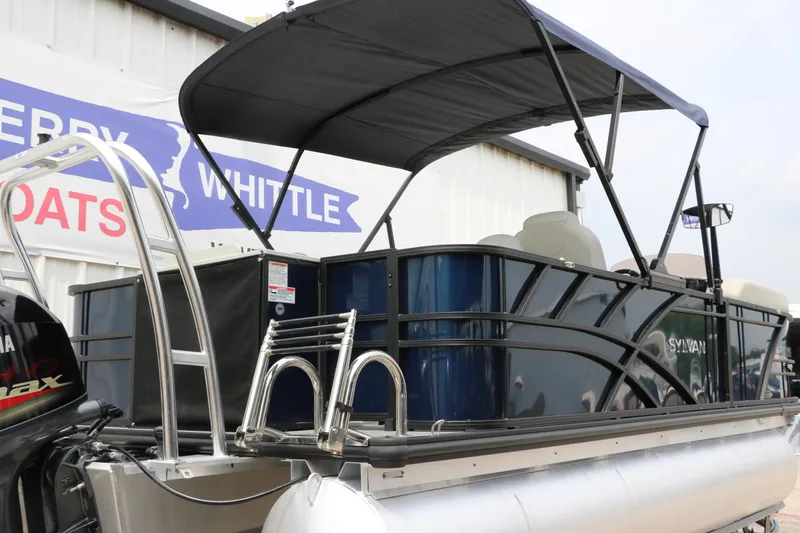 Slide: The Image of 2023 Sylvan Mirage Fish 820 Party Fish pontoon boat with canopy, docked near a building. - 3