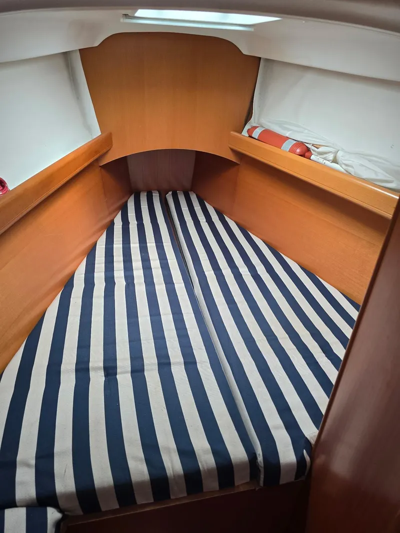 Slide: The Image of Beneteau First 40.7 2000 cabin with striped bedding and wooden interior. - 22