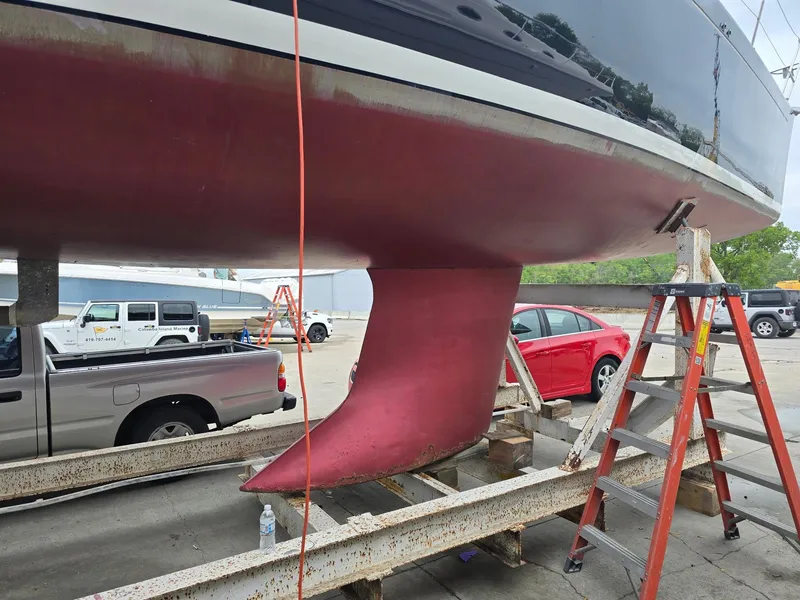 Slide: The Image of Beneteau First 40.7 sailboat keel, 2000 model, on dry dock with surrounding vehicles. - 4