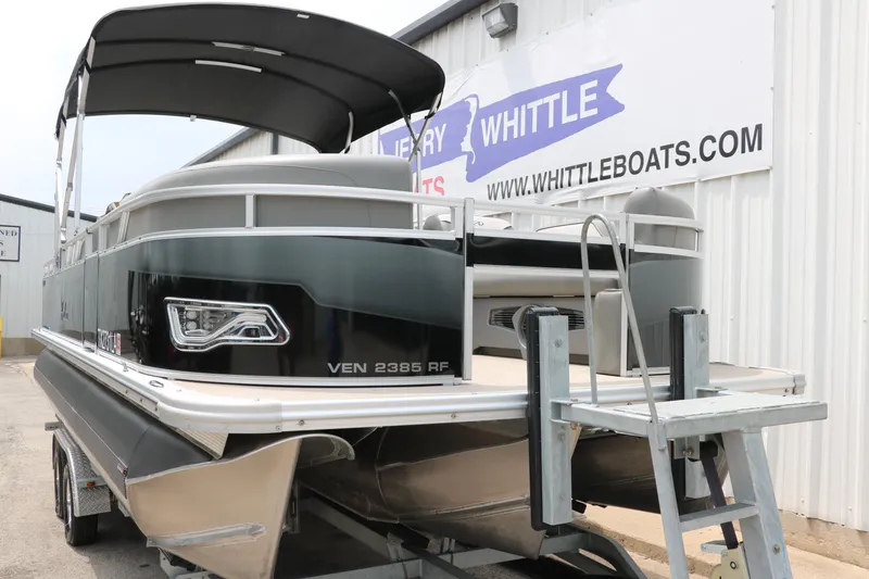 Slide: The Image of 2023 Avalon Venture 2385 RF pontoon boat on trailer, black exterior, docked at dealership. - 10
