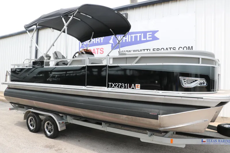 Slide: The Image of 2023 Avalon Venture 2385 RF pontoon boat on trailer, black exterior, parked outside. - 12
