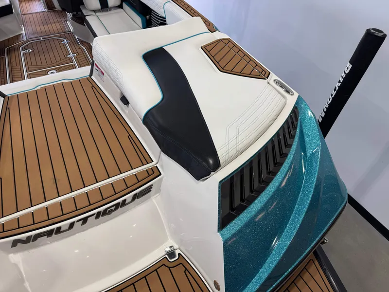 Slide: The Image of 2019 Nautique Super Air Nautique G25 boat interior with teak flooring and cushioned seating. - 11