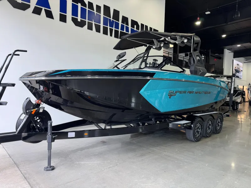 Slide: The Image of 2019 Nautique Super Air Nautique G25 boat in showroom, black and teal design, on trailer. - 2