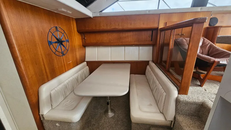 Slide: The Image of 1995 Silverton 41 Convertible interior with dining area, featuring wood paneling and white cushioned seating. - 21