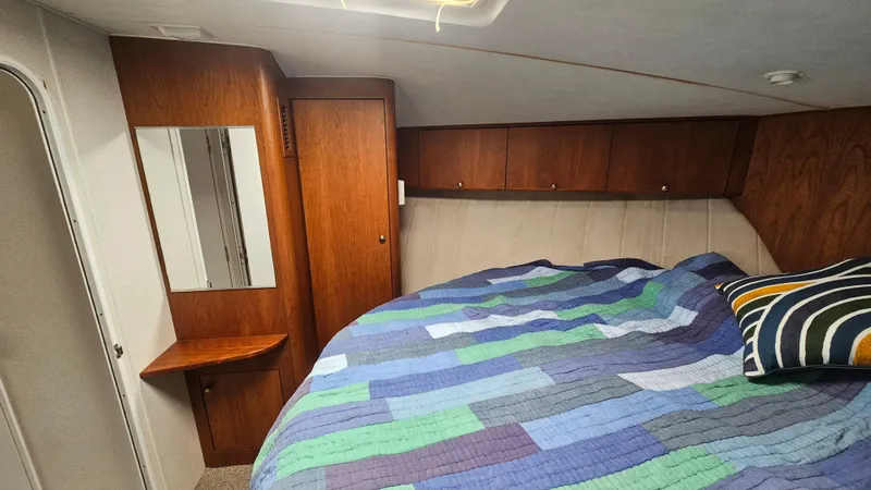 Slide: The Image of 1995 Silverton 41 Convertible cabin with colorful quilt and wooden cabinetry. - 24