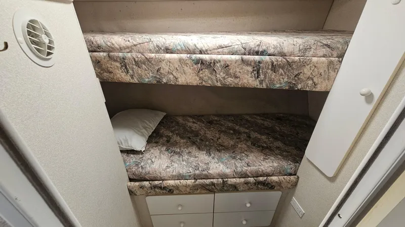 Slide: The Image of Bunk beds in a 1995 Silverton 41 Convertible boat cabin, featuring patterned bedding. - 30