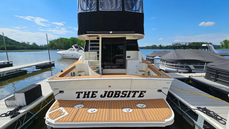 Slide: The Image of 1995 Silverton 41 Convertible boat docked, named "The Jobsite," with wooden deck and clear sky. - 5