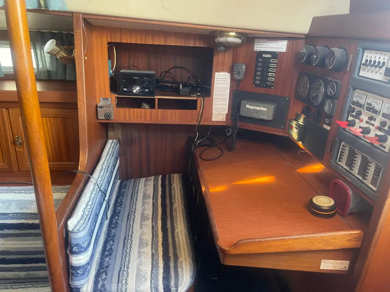 Slide: The Image of Navigation station inside 1984 Hanseat 37 sailboat with striped seating and control panels. - 21
