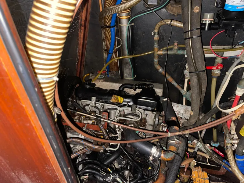 Slide: The Image of Engine compartment of a 1984 Hanseat 37 sailboat, showcasing various hoses and mechanical components. - 28