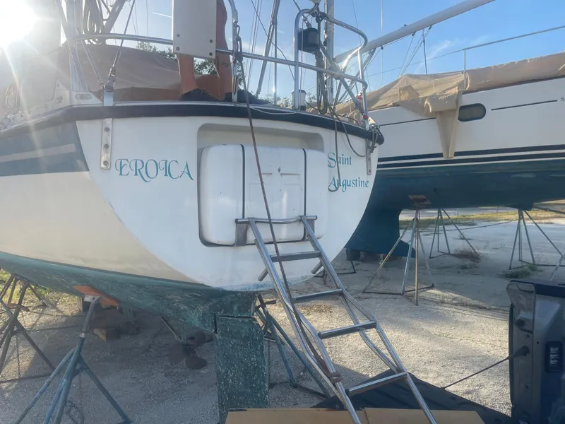 Slide: The Image of 1984 Hanseat 37 sailboat on dry dock with ladder access, sunlight illuminating the stern. - 4