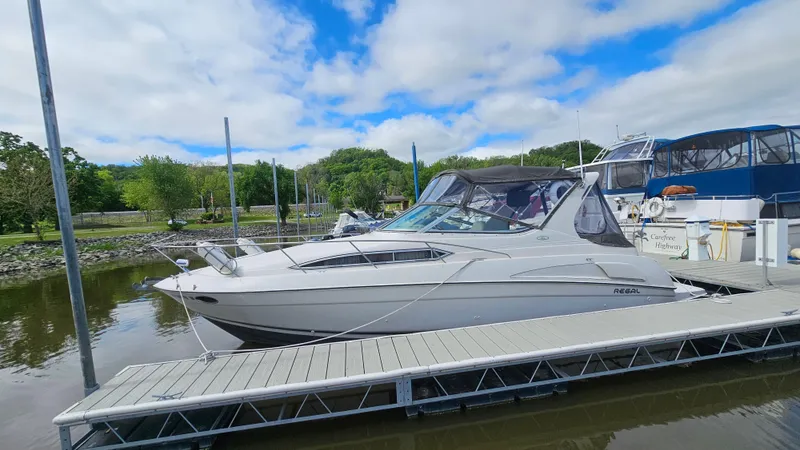 Slide: The Image of 1995 Regal Commodore 292 boat docked at a marina under a partly cloudy sky. - 4
