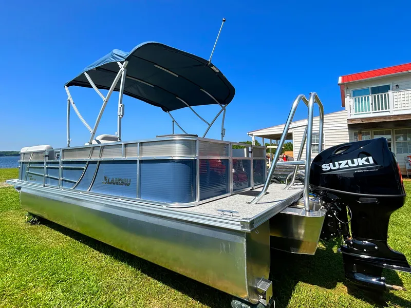 Slide: The Image of 2023 Landau Island Breeze 232 Cruise pontoon boat with Suzuki motor, docked on grassy shore. - 1