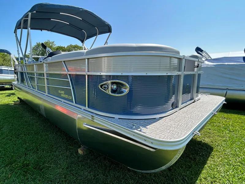 Slide: The Image of 2023 Landau Island Breeze 232 Cruise pontoon boat on grass under clear blue sky. - 2