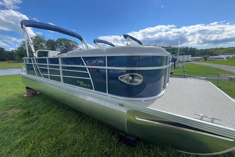 Slide: The Image of 2025 Landau Island Breeze 232 Cruise pontoon boat on grassy shore under blue sky. - 11