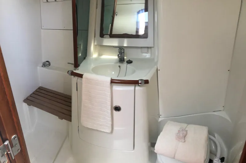 Slide: The Image of 2001 Beneteau 361 yacht bathroom with sink, mirror, and wooden bench. - 12