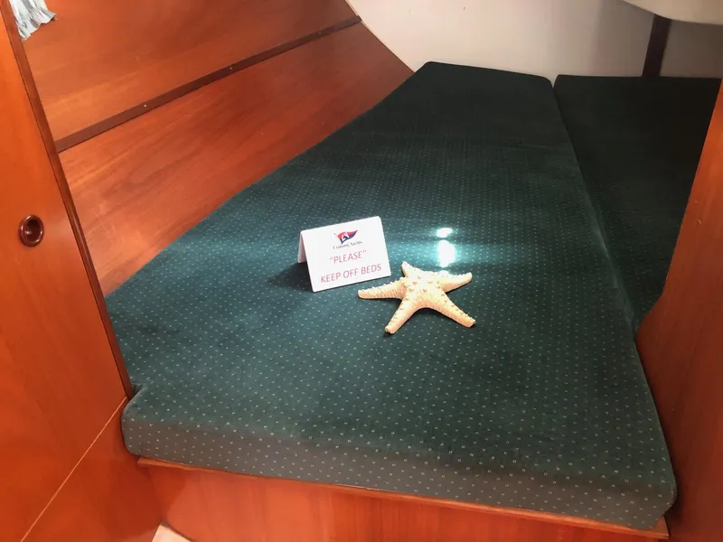 Slide: The Image of Cozy cabin interior of 2001 Beneteau 361 sailboat with green bedding and starfish decor. - 13