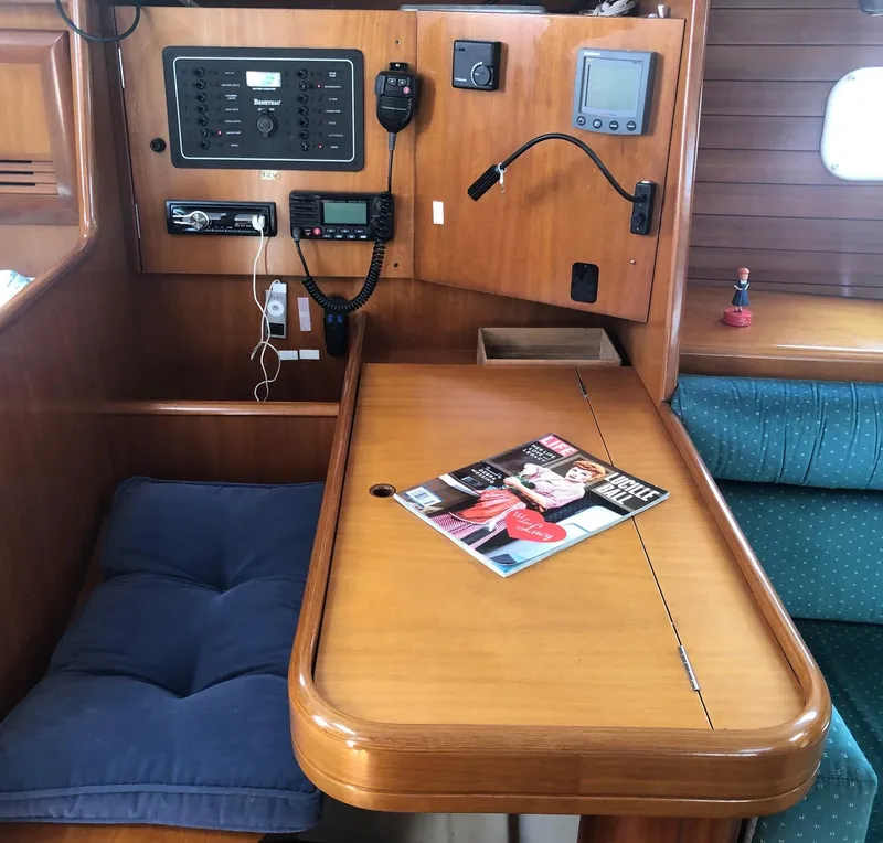 Slide: The Image of Interior of 2001 Beneteau 361 sailboat with navigation station and magazine on table. - 4