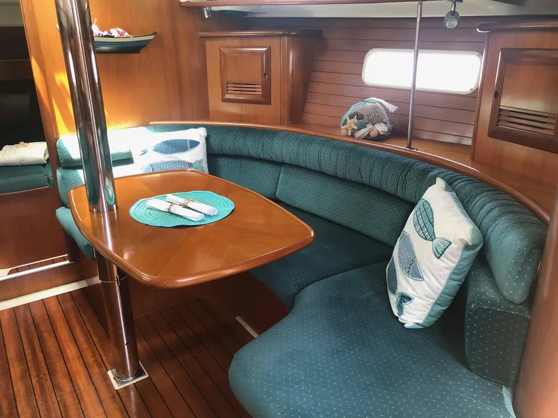 Slide: The Image of Cozy interior of 2001 Beneteau 361 sailboat with curved seating and wooden table. - 6