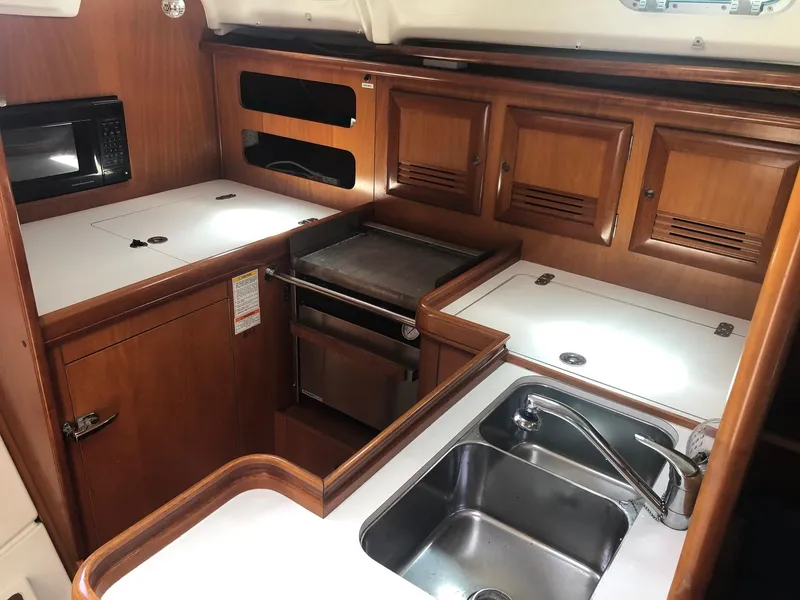 Slide: The Image of 2001 Beneteau 361 yacht kitchen with wooden cabinets, stainless steel sink, and stove. - 8