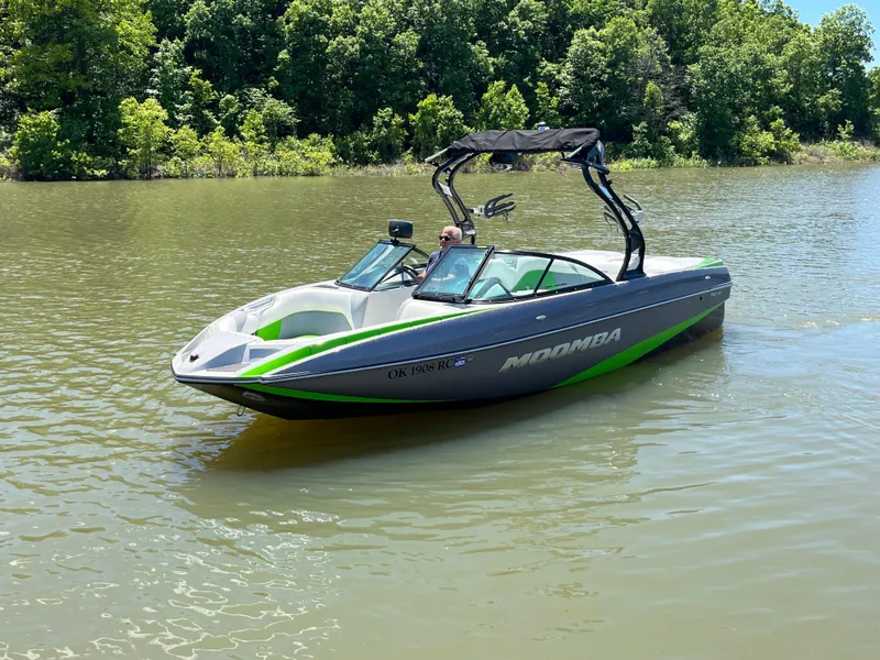 Slide: The Image of 2016 Moomba Mojo boat on a calm lake with lush green trees. - 11