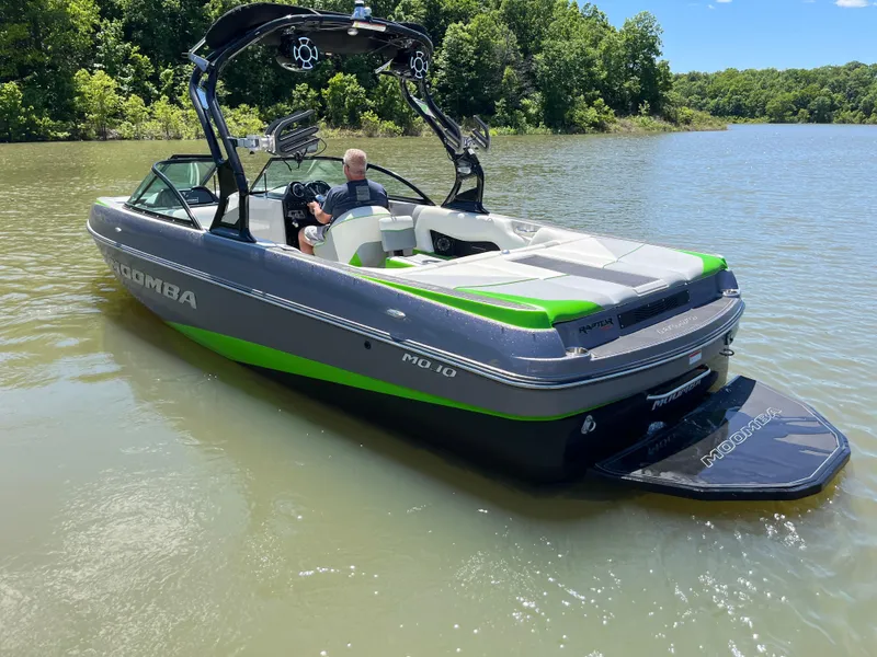 Slide: The Image of 2016 Moomba Mojo boat on a lake, featuring a sleek design and vibrant green accents. - 2