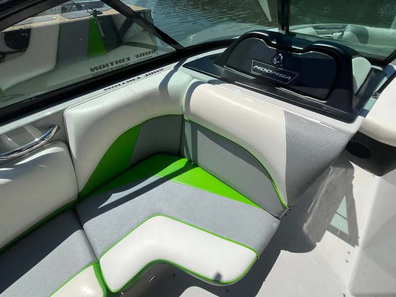 Slide: The Image of 2016 Moomba Mojo boat interior with white, gray, and green seating near water. - 25