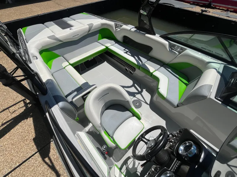 Slide: The Image of 2016 Moomba Mojo boat interior with green and gray seating, steering wheel, and dashboard. - 27