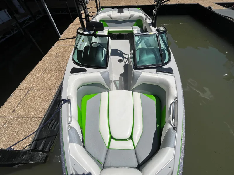 Slide: The Image of 2016 Moomba Mojo boat with green and gray interior, docked on calm water. - 28