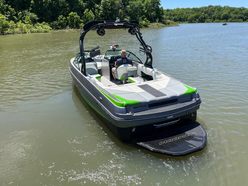 Slide: The Image of 2016 Moomba Mojo boat on a calm lake with lush green surroundings. - 3