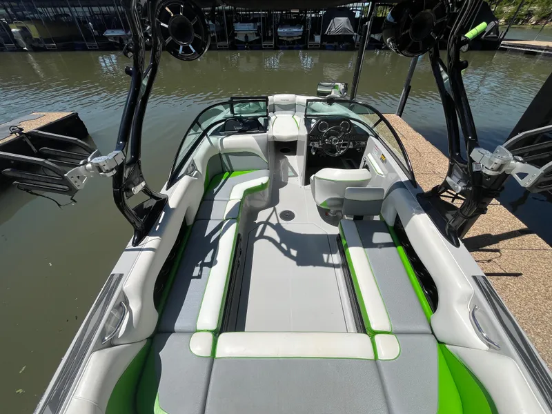 Slide: The Image of 2016 Moomba Mojo boat interior with green accents, docked on calm water. - 37