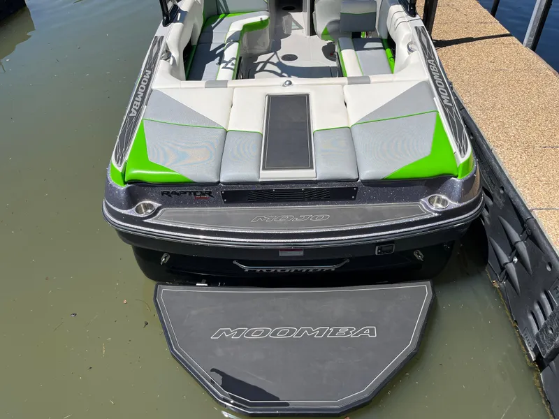 Slide: The Image of 2016 Moomba Mojo boat with green and gray interior, docked on calm water. - 39