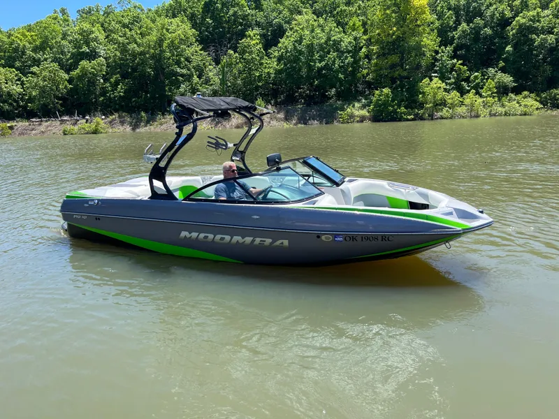 Slide: The Image of 2016 Moomba Mojo boat on a calm lake with lush green trees. - 6