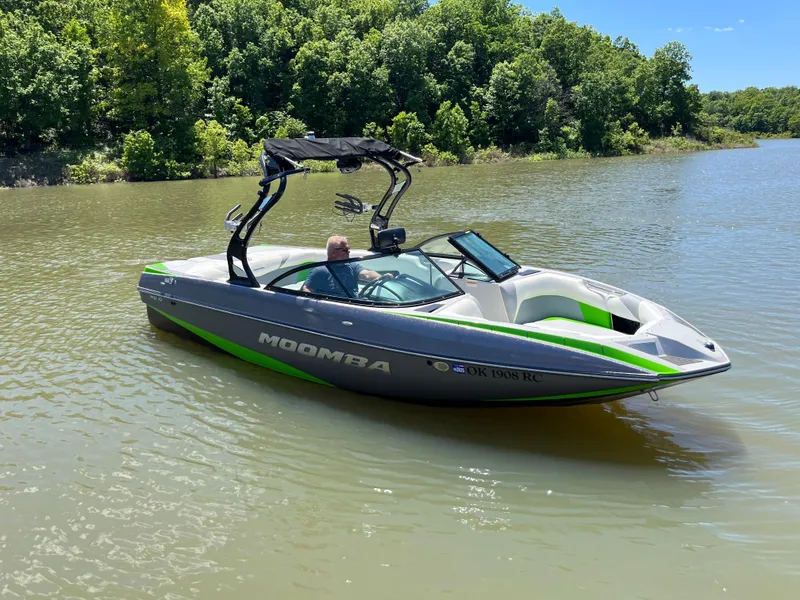Slide: The Image of 2016 Moomba Mojo boat on a calm lake with lush green trees. - 7
