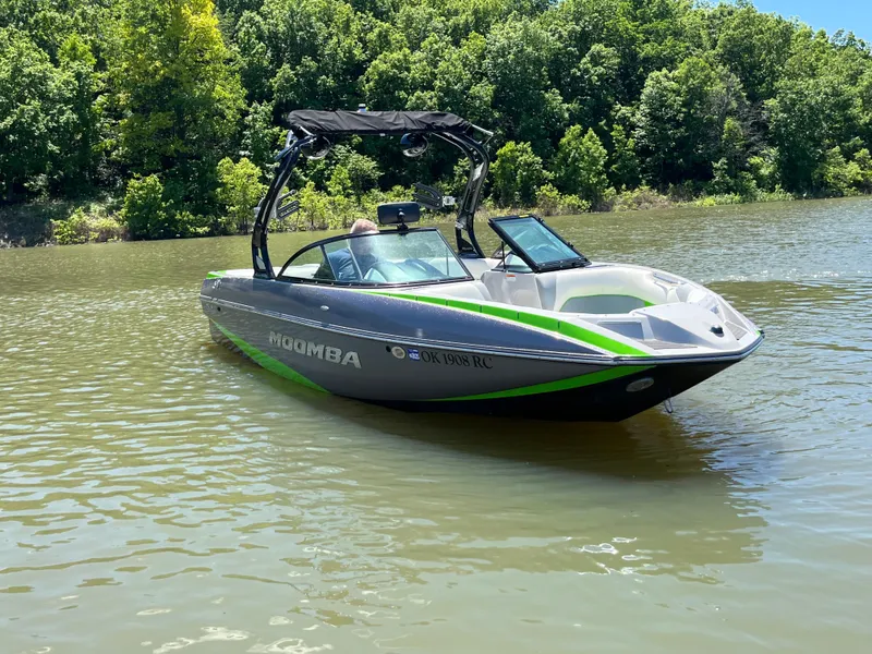 Slide: The Image of 2016 Moomba Mojo boat on a calm lake with lush green trees in the background. - 9