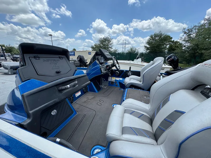 Slide: The Image of 2021 Nitro Z21 boat interior with blue accents and comfortable seating under a cloudy sky. - 2