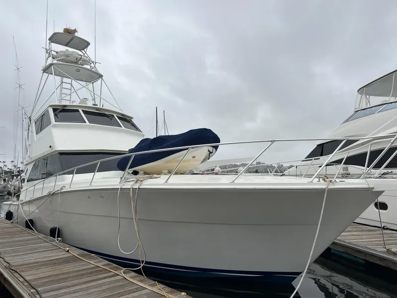The Image of 2000 Viking 58 Enclosed Bridge yacht docked at marina under cloudy sky. - 1