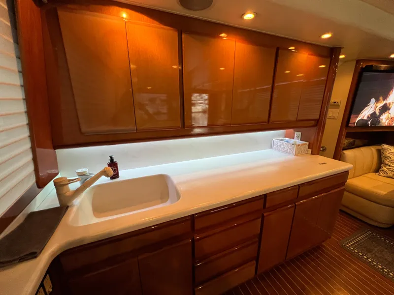 Slide: The Image of Luxurious kitchen interior of 2000 Viking 58 Enclosed Bridge yacht with wooden cabinets and modern lighting. - 12