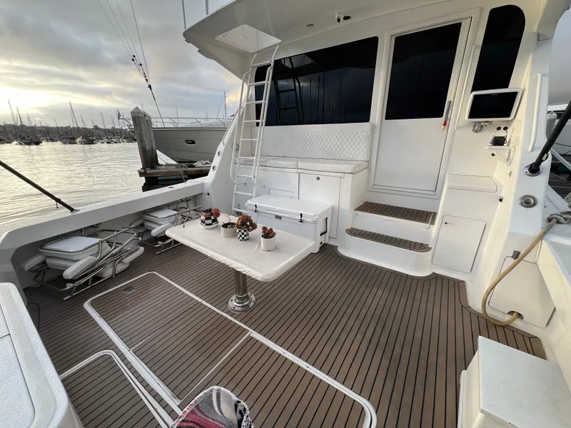 Slide: The Image of Viking 58 Enclosed Bridge 2000 yacht deck with table, chairs, and marina view. - 4