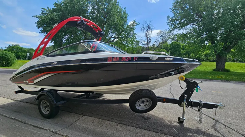 Slide: The Image of 2019 Yamaha AR195 boat on trailer, parked on street with lush greenery background. - 3