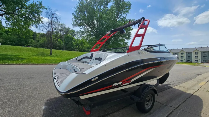 Slide: The Image of 2019 Yamaha AR195 boat on trailer, parked on a sunny street with trees and buildings. - 4