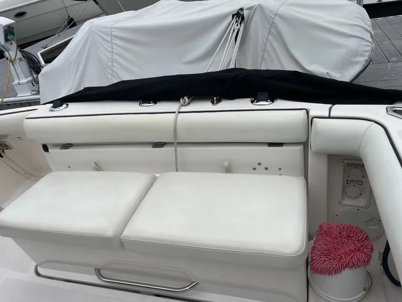 Slide: The Image of 2003 Tiara Yachts 3500 Open boat seating area with white cushions and docked cover. - 24