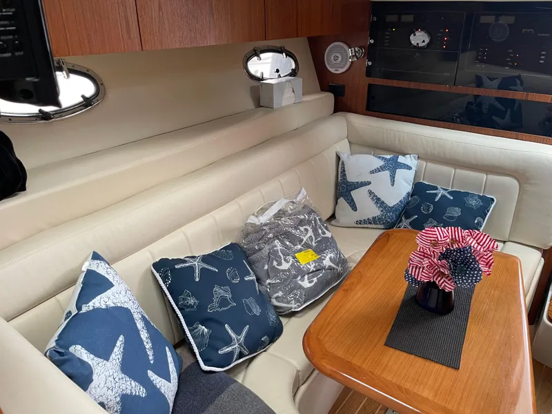 Slide: The Image of 2003 Tiara Yachts 3500 Open interior with starfish-themed cushions and wooden table. - 35
