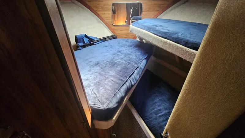 Slide: The Image of 1982 Chris-Craft 381 Catalina cabin with blue cushioned bunk beds and wooden interior. - 12
