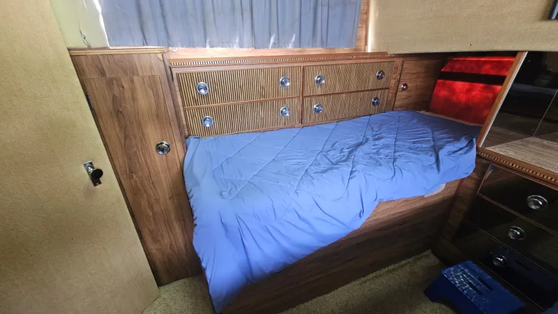 Slide: The Image of 1982 Chris-Craft 381 Catalina cabin interior with blue bedding and wooden cabinetry. - 16