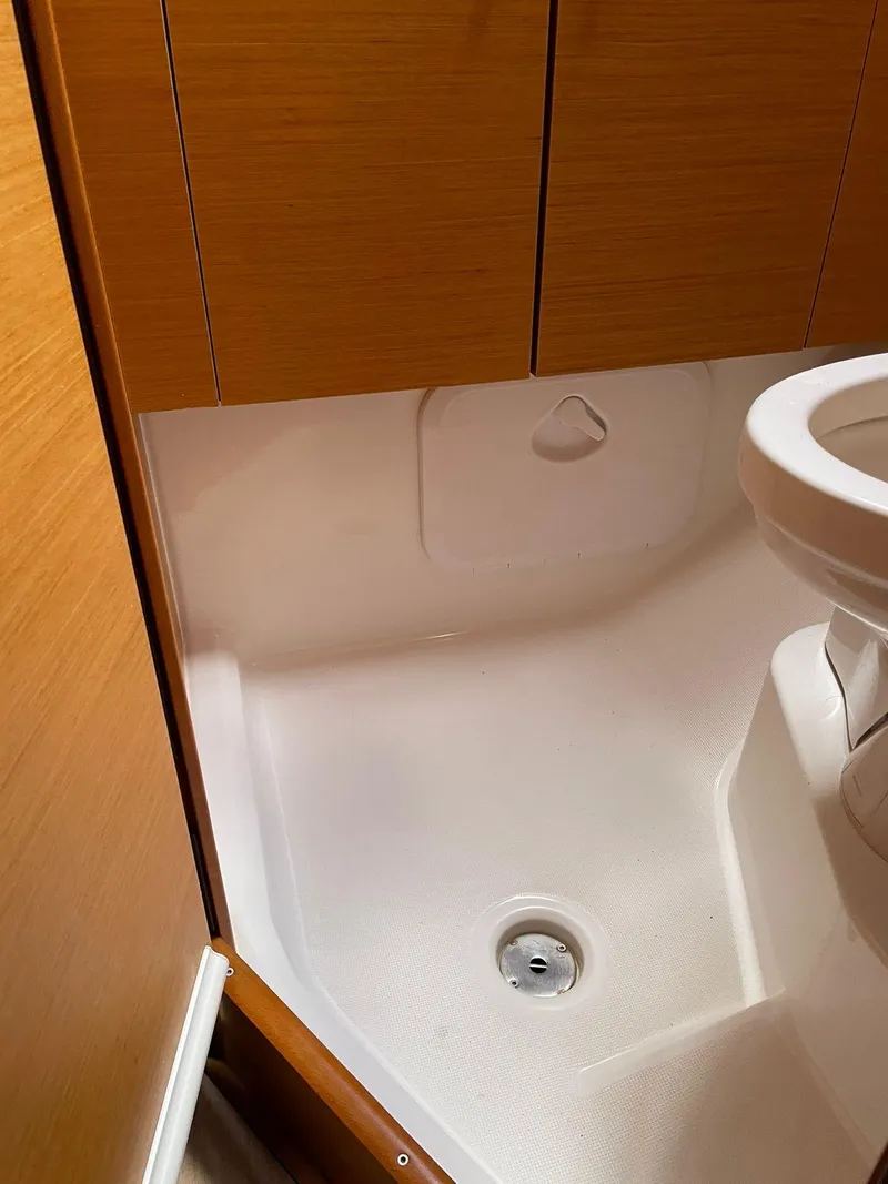 Slide: The Image of Bathroom interior of 2017 Jeanneau Sun Odyssey 479 yacht, featuring wooden cabinetry and shower area. - 25