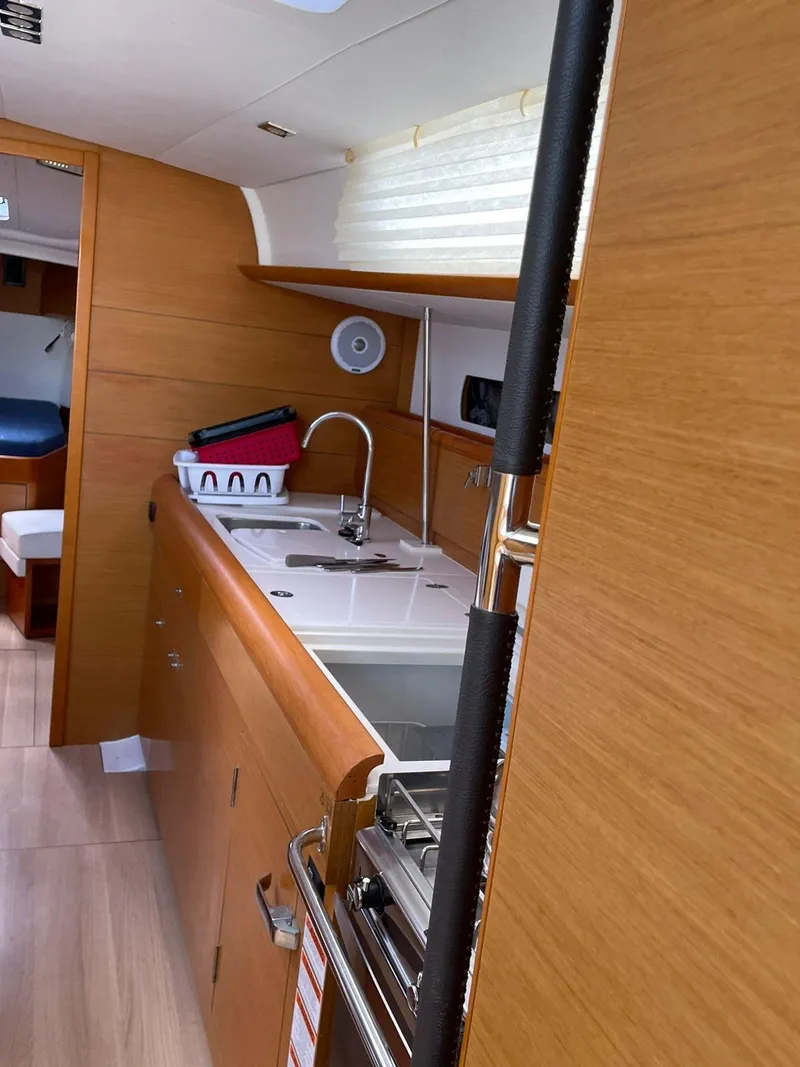 Slide: The Image of 2017 Jeanneau Sun Odyssey 479 yacht interior kitchen with wooden cabinetry and modern fixtures. - 33