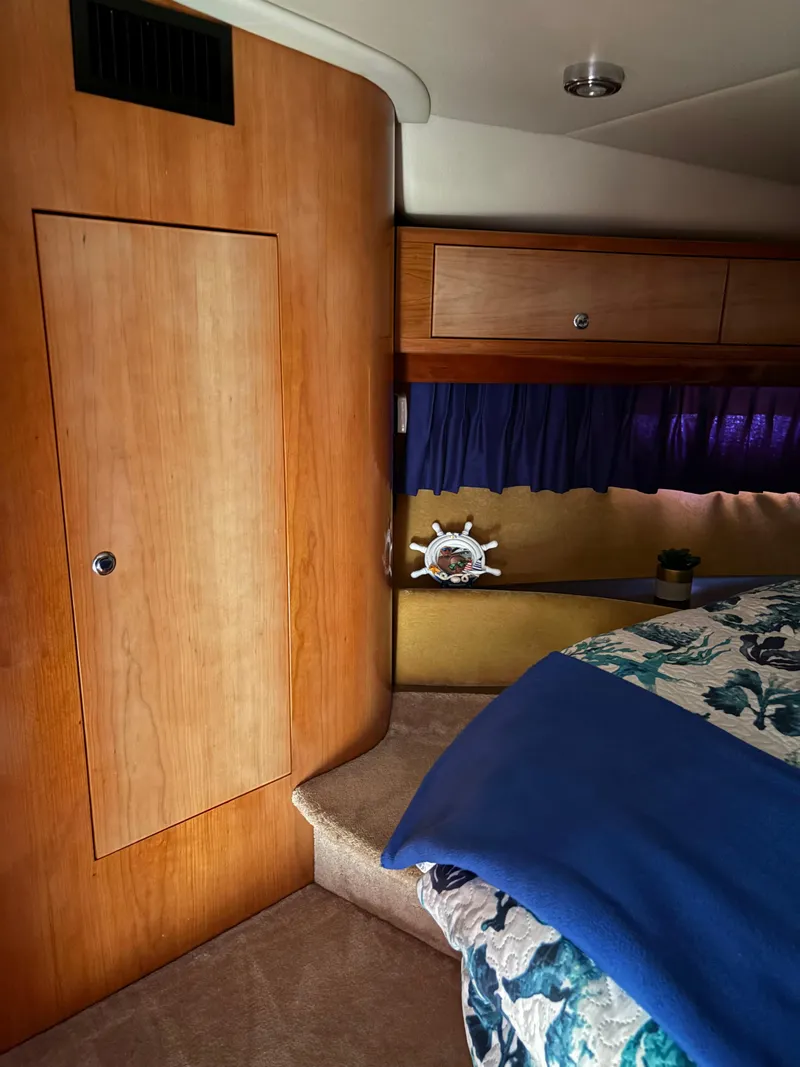 Slide: The Image of 2003 Regal 4260 Express Cruiser cabin interior with wood paneling and cozy bedding. - 19