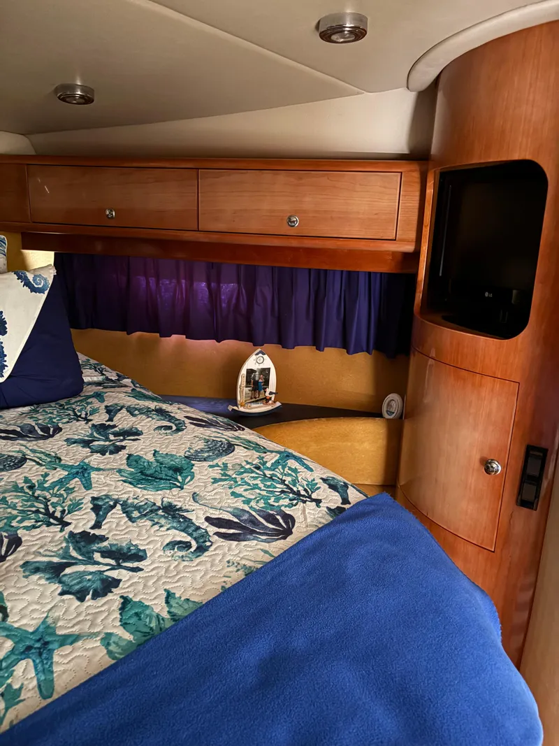 Slide: The Image of 2003 Regal 4260 Express Cruiser cabin with floral bedding and wooden cabinetry. - 20