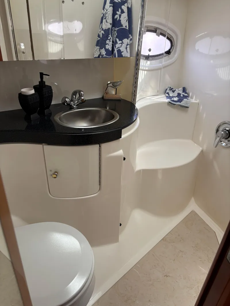 Slide: The Image of 2003 Regal 4260 Express Cruiser bathroom with sink, toilet, and porthole window. - 22